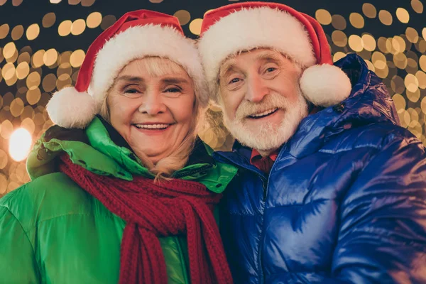 引退した2人の年金受給者グレーの白い髪の人々愛情のあるカップルの女性男性お祝いのX-masクリスマスジョリーイベント歩く外の照明の下でサンタクラスのヘッドウェア — ストック写真