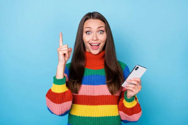 Portret opgewonden meisje gebruik smartphone denken gedachten krijgen ongelooflijk idee wat sms typen sociaal netwerk verhogen index vinger omhoog slijtage regenboog stijl trui geïsoleerde blauwe kleur achtergrond — Stockfoto