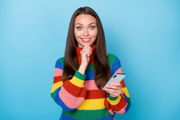 Foto von intelligenten kreativen Mädchen verwenden Smartphone Social Media Blogging berühren Finger Kinn genießen Chat SMS-Eingabe tragen Regenbogen-Stil Pullover isoliert über blauem Hintergrund — Stockfoto