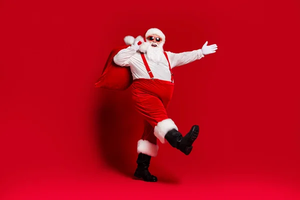 Pleine longueur corps taille vue de son il attrayant joyeux père Noël gai portant grand sac livraison vente discount va isolé lumineux vif éclat vibrant fond de couleur rouge — Photo