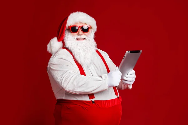 Profiel side view portret van zijn aantrekkelijke vrolijke vet wit-harige Kerstman met behulp van gadget ebook lezen e-mail brief geïsoleerde heldere levendige glans levendige rode bordeaux kastanjebruin kleur achtergrond — Stockfoto