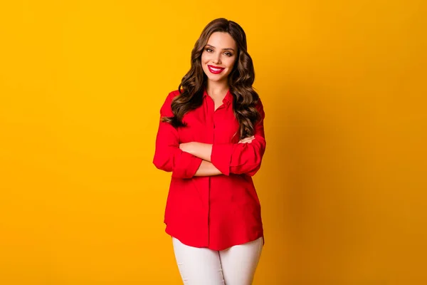 Foto de muito encaracolado senhora de negócios brilhante pomade mandona pessoa amigável sorrir braços cruzados usar escritório vermelho camisa branca calças isoladas amarelo vívido cor fundo — Fotografia de Stock