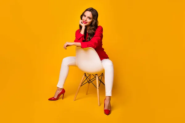魅力的なビジネスの女性の完全な体の写真は足の間に居心地の良い椅子に座るリーン頭の顔の腕陽気な赤いシャツの白いズボン高ヒール分離黄色鮮やかな色の背景 — ストック写真