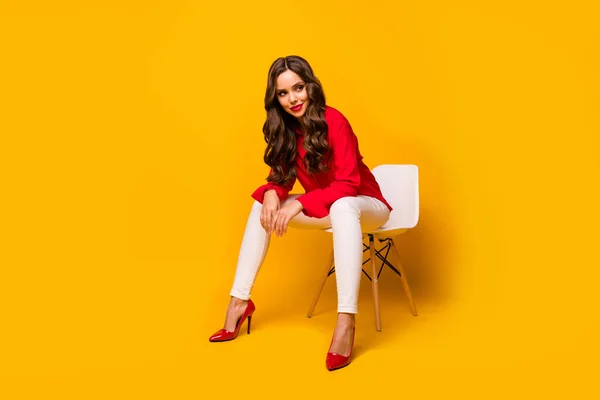 Полная длина фото привлекательной шикарной деловой леди сидеть босс удобный стул кокетливое настроение смотреть сбоку пустое пространство носить красную рубашку белые брюки на высоких каблуках изолированные желтый яркий цвет фона — стоковое фото