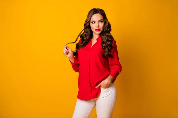 Foto de atraente flerte mandona senhora de negócios olhar lado espaço vazio jogando longo curl desgaste vermelho camisa de escritório branco calças isoladas amarelo brilhante cor de fundo — Fotografia de Stock