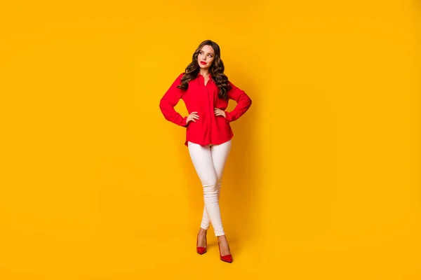 Plná délka fotografie atraktivní obchodní dáma držet ruce boky vypadají překvapeně prázdný prostor snílek nosit červenou kancelářskou košili bílé kalhoty vysoké podpatky izolované žluté zářivé barvy pozadí — Stock fotografie