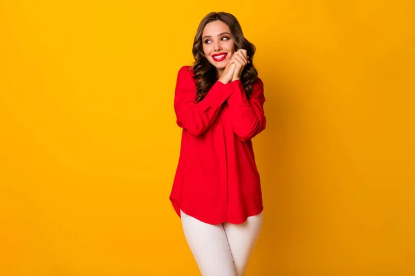 Foto av attraktiva roliga lockigt dam hålla händerna tillsammans ser överlycklig sida tomt utrymme formalwear rött kontor skjorta vita byxor isolerad ljus gul färg bakgrund — Stockfoto