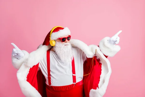 Фото уверенного современного фанки Санта Клауса слушать наушники рождественские песни стерео радио танец ношение подтяжки солнцезащитные очки головные уборы изолированы на пастельном фоне цвета — стоковое фото