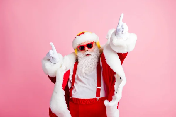 Bild av skäggiga moderna tomten Claus njuta lyssna jul jul låtar heaphones dans höja fingrar bära solglasögon handskar huvudbonad över pastell färg bakgrund — Stockfoto