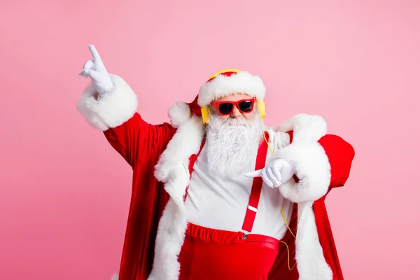 ファンキーでクールな腹部の写真サンタクラスは、リスニングヘッドフォンをお楽しみくださいx-masクリスマスソングラジオは指を上げるダンスウェアサングラスサスペンダーパステルカラーの背景に隔離されたヘッドウェア — ストック写真
