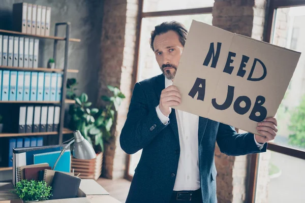 Portrét jeho depresivní nezaměstnaný kvalifikovaný odborník zaměstnavatel nosí bundu drží v ruce plakát říká, že potřebují práci v moderním podkroví průmyslové cihly styl interiéru pracoviště — Stock fotografie
