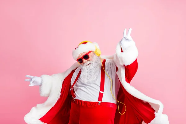 Photo moderne funky santa claus écouter x-Noël Noël stéréo radio utiliser écouteurs lever les mains doigts porter style élégant gros ventre costume pantalon casque isolé couleur pastel fond — Photo