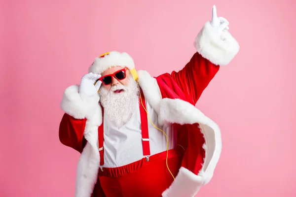 写真ファンキーなクールな脂肪のサンタクラスは、耳を傾けるを楽しむクリスマスのヘッドフォンラジオダンスジョリー新年イベントは指を上げるサングラスサスペンダーキャップヘッドウェア隔離されたパステルカラーの背景を着用 — ストック写真