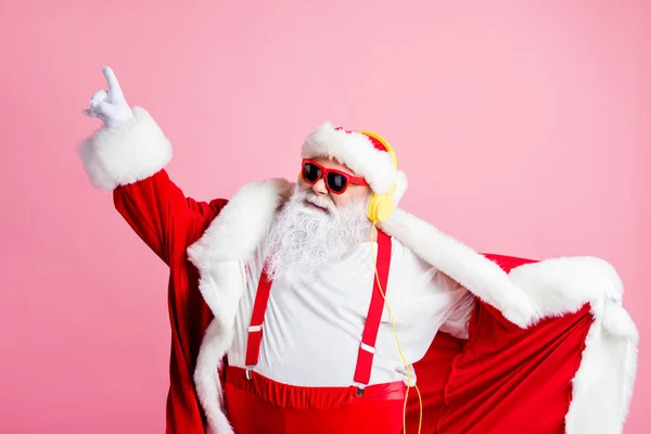 写真クールなファンキーなサンタクラス大きな腹部リッスンx-masクリスマスラジオの歌ヘッドフォンダンス新年のイベントは、指の摩耗ヘッドウェアサスペンダーサングラス孤立パステルカラーの背景を上げる — ストック写真