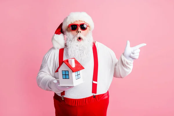 Güzel, çekici, afallamış Noel Baba 'nın portresi elinde tuttuğu ev fotokopi alanını gösteriyor banka mülkiyet sigortası yenilik hizmeti sunuyor pembe pastel arka planda izole edilmiş. — Stok fotoğraf