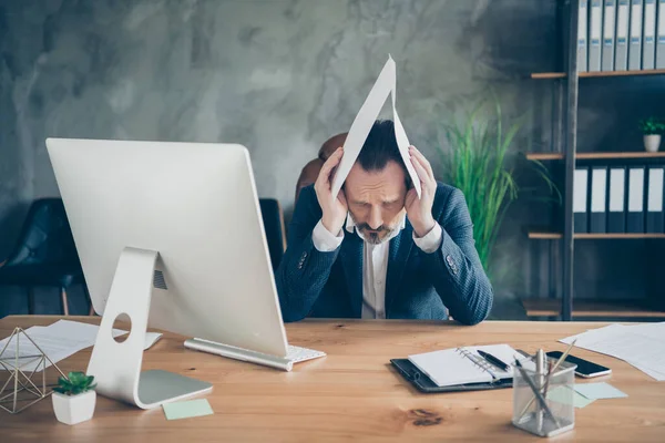 Retrato de su hombre apuesto deprimido experto en la celebración de documento de papel en la cabeza como el caso de la ley del techo corte economía de juicio disminución de seguros en la moderna estación de trabajo de pared de hormigón industrial — Foto de Stock