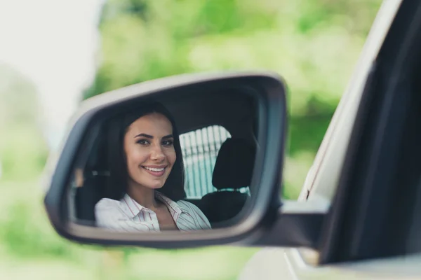 De cerca la foto de la chica jinete conductor alegre alegre positivo mirar a sí misma en vidrio retrovisor sentado coche viaje centro de la ciudad fuera —  Fotos de Stock