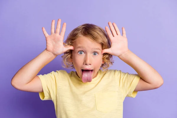 Retrato de criança pequena menino fazer engraçado rosto mostrar língua para fora isolado sobre cor violeta fundo — Fotografia de Stock