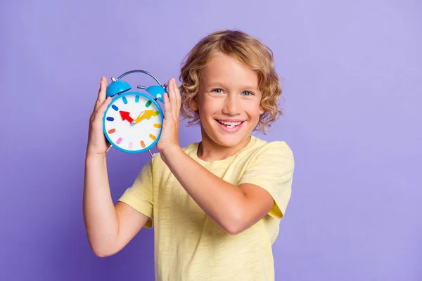 Foto de menino alegre positivo ouvir anel relógio isolado sobre fundo cor pastel violeta — Fotografia de Stock