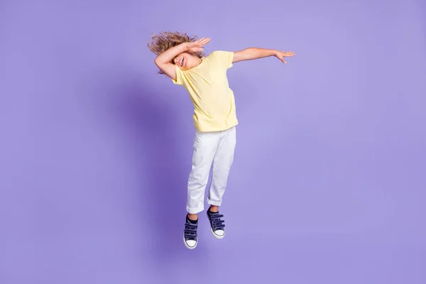 Full body foto van dabber kleine jongen springen close armen gezicht dragen wit geel t-shirt broek geïsoleerd over paarse kleur achtergrond — Stockfoto