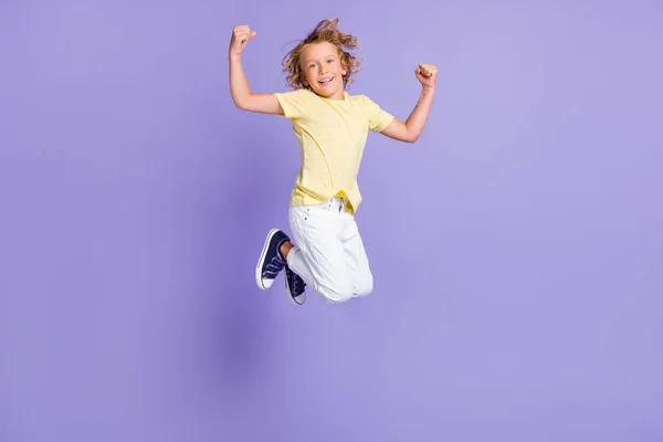 Pleine longueur photo de garçon positif saut montrer biceps porter blanc jaune t-shirt pantalon isolé sur fond de couleur pourpre — Photo