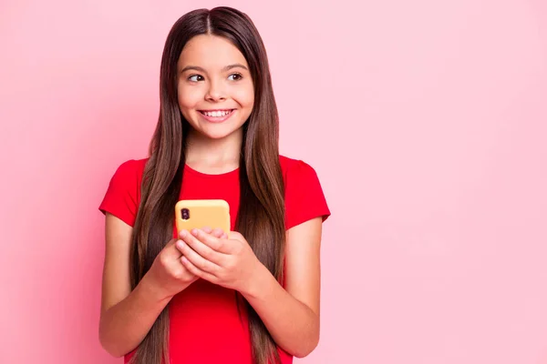 Foto de niña latina uso teléfono inteligente mirada espacio vacío desgaste camiseta roja aislada sobre fondo de color pastel — Foto de Stock