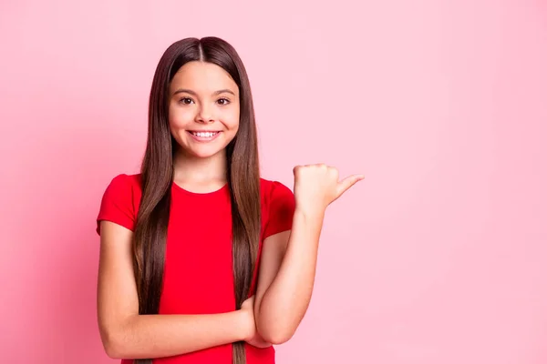 Photo of lovely sweet little lady long hairdo skrzyżowane ręce pewnie bezpośredni wskazują kciuk palec puste miejsce błyszczący uśmiech nosić casual czerwony t-shirt odizolowany różowy kolor tła — Zdjęcie stockowe