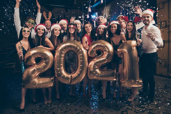 Foto retrato de gente alegre lanzando confeti usando gorras de ciervo de Santa levantando las manos sosteniendo globos 2021 —  Fotos de Stock