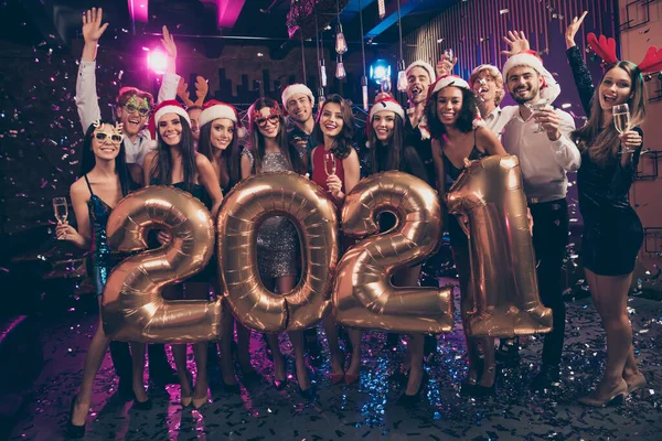 Foto retrato de personas felices celebrando el año nuevo 2021 levantando las manos sosteniendo copas de champán usando ridículos trajes de cabeza de renos festivos —  Fotos de Stock