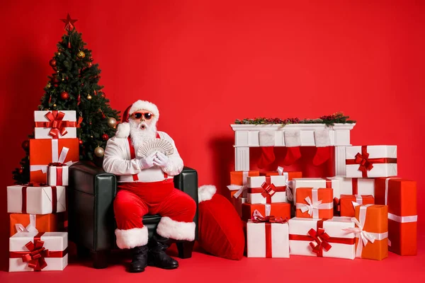 他的肖像漂亮迷人的时髦的脂肪惊奇地发现富有的圣诞老人坐在扶手椅上手握现金哇，鲜亮的红色背景 — 图库照片