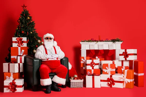 Portret van zijn hij aantrekkelijke funky vet overgewicht vrolijk blij Santa vader zitten in fauteuil in ingerichte woonkamer feestelijke geest geïsoleerd helder levendig glans levendige rode kleur achtergrond — Stockfoto