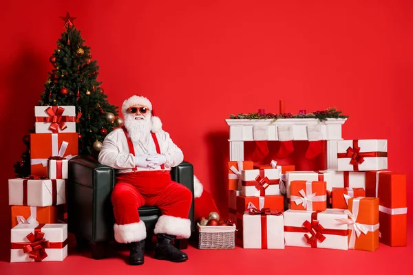 他的形象吸引人的时髦肥胖超重快乐的圣诞老人爷爷坐在扶手椅客厅里圣诞节前夕与世隔绝的明亮而生动的红色背景 — 图库照片