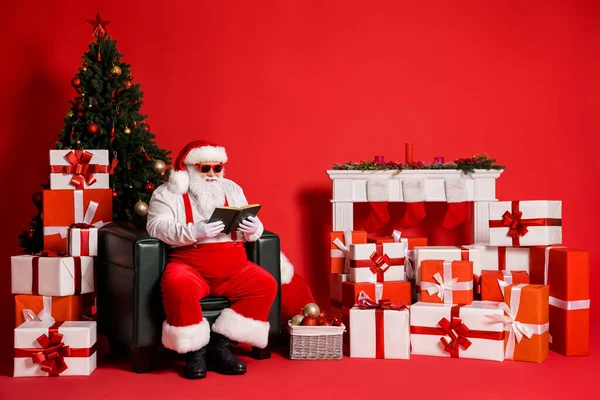 他的形象吸引人的时髦肥胖超重快乐专注聪明聪明的圣诞老人坐在扶手椅客厅看书孤立明亮生动的光泽鲜红的背景 — 图库照片