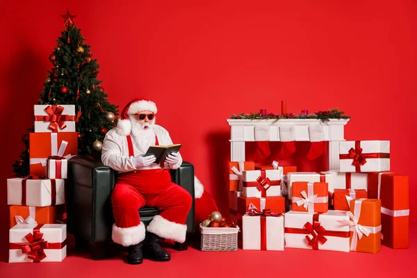 Portret van zijn hij aantrekkelijke funky vet overgewicht verbaasd verbijsterd Kerstman zitten in fauteuil woonkamer lezen interessant boek geïsoleerd helder levendig glans levendige rode kleur achtergrond — Stockfoto