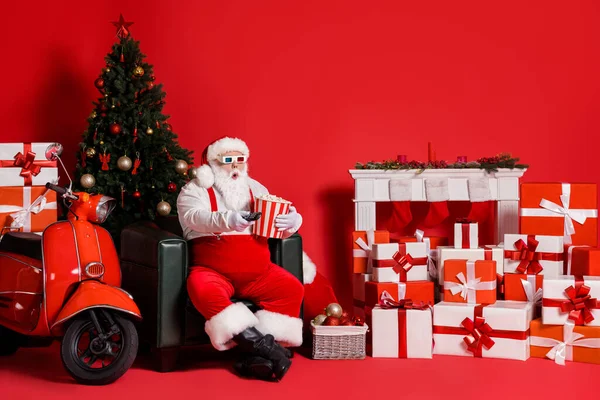 Foto de comprimento total de Papai Noel espantado interruptor de controle 3d filme segurar caixa de milho pop isolado no fundo de cor vermelha com x-mas ornamento — Fotografia de Stock