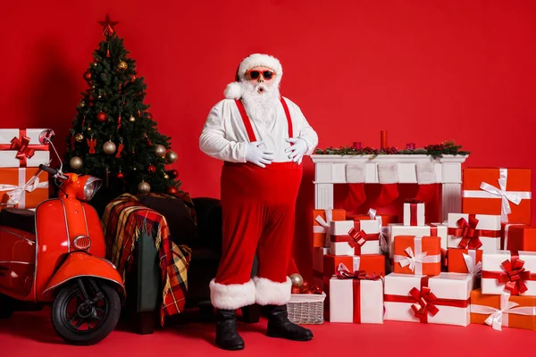 Noel Baba 'nın tam boy fotoğrafı, kırmızı renkli arka planda izole edilmiş, büyük karın bölgesine dokunur. — Stok fotoğraf