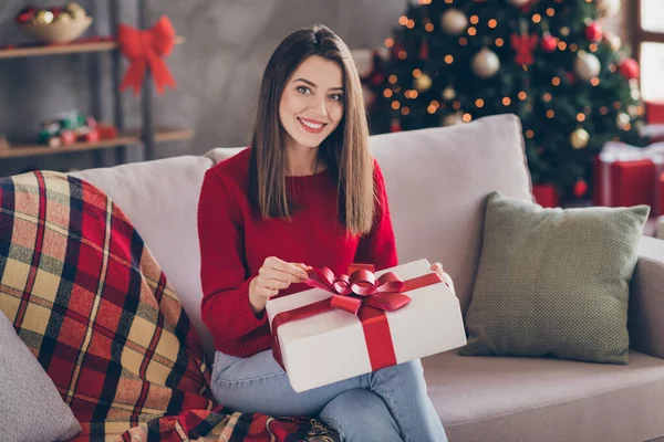 Pozitif kızın fotoğrafı kanepe açık, Noel hediyesi kutusu açık. Evin içinde yeni yıl süsleriyle kurdele çek. — Stok fotoğraf