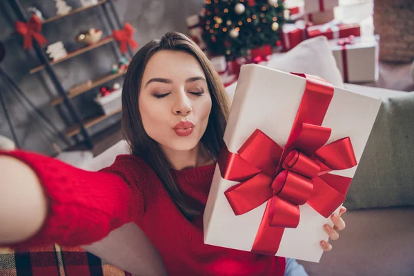 Güzel bir kızın hediye kutusundaki fotoğrafı Selfie 'nin hava öpücüğü göndermesini sağlayın. Kapalı bir evde oturup Noel süsü takın. — Stok fotoğraf