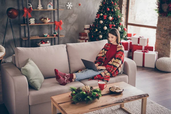 Foto der hübschen Dame sitzen Sofa halten Laptop Beine eingeben tragen karierte rote Pullover Socken Jeans in dekoriert x-mas Wohnzimmer drinnen — Stockfoto