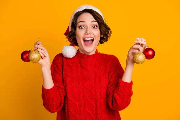 Foto di bella allegra divertente eccitata signora celebrare le vacanze invernali tenere palle di Natale presenti decorare albero verde indossare cappello di Babbo Natale rosso maglia maglione isolato colore giallo sfondo — Foto Stock