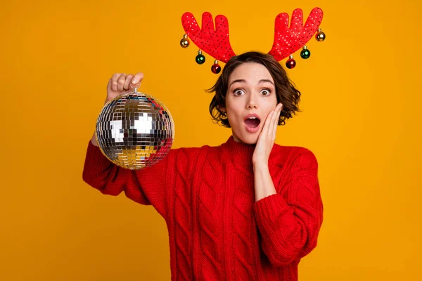Party is canceled. Photo of pretty scared lady hold disco ball ready theme party celebration bad news wear decor headband x-mas horns red knitted sweater isolated yellow color background — Stock Photo, Image