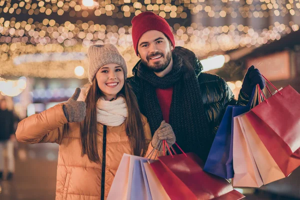 Μαύρη Παρασκευή. Φωτογραφία δύο ανθρώπων φοιτητές φίλοι κατέχουν τσάντες ψώνια δείχνουν τον αντίχειρα μέχρι την πινακίδα κάτω από τα Χριστούγεννα Χριστούγεννα Χριστούγεννα εξωτερικό φωτισμό — Φωτογραφία Αρχείου