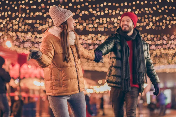 Фото веселої веселої пари гуляють на Різдвяному вечірньому заході під відкритим небом вогні носять пальто шапки шарф — стокове фото