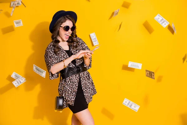 Photo of positive crazy girl travel trip waste spend dollars air fly money credit bank cashback wear headwear skirt sunglass isolated over yellow color background — Stock Photo, Image