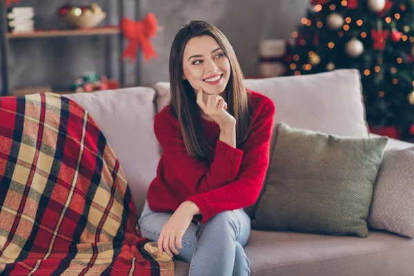 Pozitif kızın oturduğu koltuğun fotoğrafı. Evde kırmızı kazak giyip Noel geleneği süslemesi yaptırdığını düşün. — Stok fotoğraf