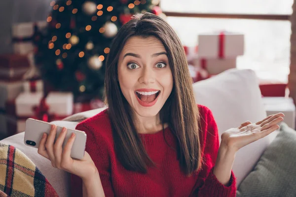 Портрет сумасшедшей девушки держать смартфон x-mas noel сделки концепции сидеть диван в доме в помещении с рождественским украшением — стоковое фото