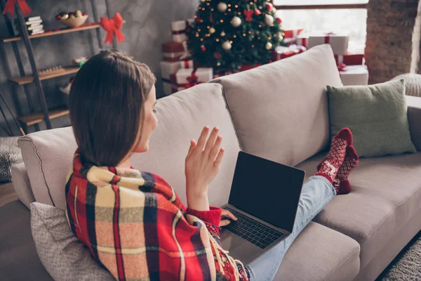 Photo of charming lady sit sofa hold netbook waving palm wear blanket red socks jeans in decorated x-mas living room indoors