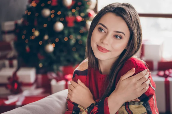 Foto de linda menina sorriso envolto cobertor xadrez abraçar auto olhar desgaste camisola vermelha na sala de estar decorada x-mas dentro de casa — Fotografia de Stock