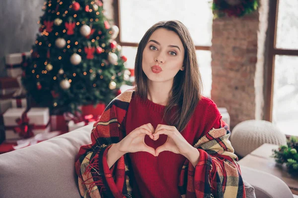 Foto di bella donna avvolto coperta spettacolo mani figura del cuore indossare maglione rosso in decorato x-mas soggiorno al chiuso — Foto Stock