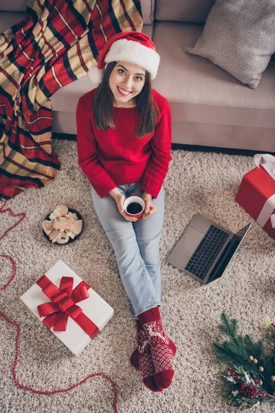 Hoch über dem Winkel vertikales Foto der Dame sitzen Boden Laptop halten Tasse tragen roten Pullover Socken Jeans in dekoriert Weihnachten Wohnzimmer drinnen — Stockfoto